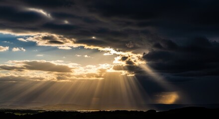 Dramatic golden sunbeams breaking through dark storm clouds at sunset.