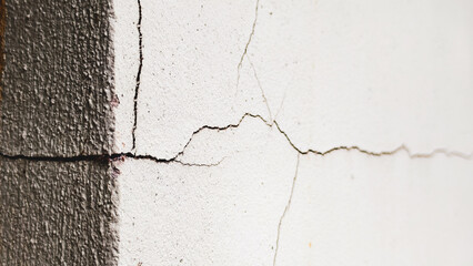 Cracked wall with white paint : A close-up captures the stark contrast of a cracked wall revealing its wear. A symbol of aging structure, highlighting the effects of time on a weathered surface.