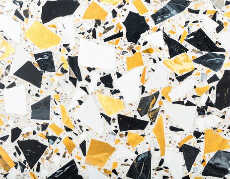 Overhead terrazzo stone surface with larger bold chips in contrasting black, white and soft gold, clean background