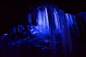 洞窟の中にある凍った柱に青い暗い背景
