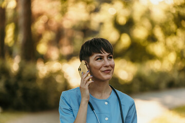 Female doctor talking on smartphone in park during break