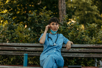 Doctor wearing scrubs and stethoscope taking break on park bench