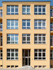 Fototapeta premium Simple residential building facade with yellow plaster and white windows 