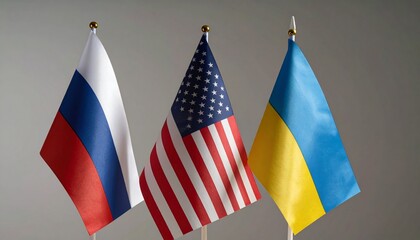 Four national flags&mdash;United States, Ukraine, Russia (x2)&mdash;standing upright on flagpoles against a blurred sunset background; symbolizing diplomacy, tension, and global relations.