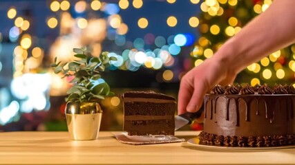 Chocolate cake being sliced on table with festive bokeh background