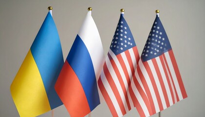 Four upright national flags&mdash;Ukraine, Russia, and two of the United States&mdash;stand side by side, symbolizing international presence and geopolitical tension, set against a neutral backdrop.