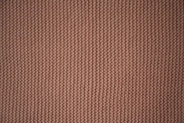 macro texture of beige knitted wool fabric. The ribbed knit pattern shows detailed yarn loops and soft fibers, creating a warm and cozy textile background. Ideal for themes related to handmade fashion
