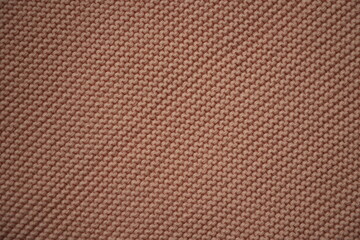 macro texture of beige knitted wool fabric. The ribbed knit pattern shows detailed yarn loops and soft fibers, creating a warm and cozy textile background. Ideal for themes related to handmade fashion