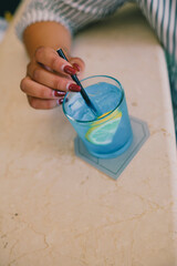 Refreshing Blue Cocktail with Lemon Slice and Stirrer in a Glass on a Coaster on a Tabletop