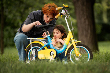 mother teaches girl to ride bicycle, discussing height of saddle.