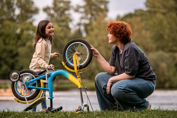 mother and little daughter playing with bicycle during walks.