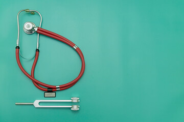red stethoscope, tuning fork on green Background, Space for Text, Space for Logo