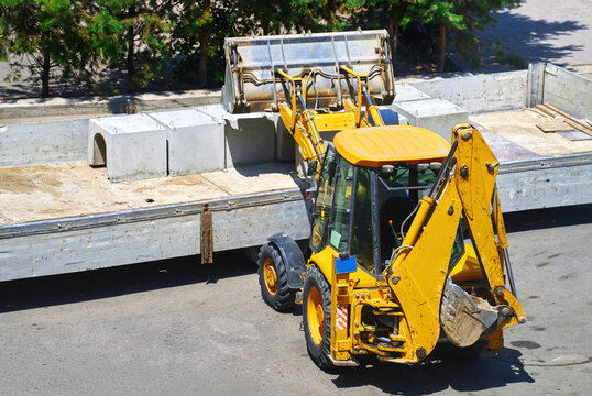 Yellow bulldozer with backhoe working on municipal road construction site