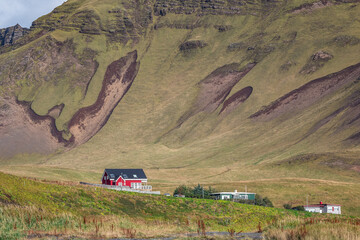 Houses nestled at the base of rugged mountainside in Vík the southernmost village in Iceland