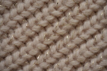 beige knitted wool fabric with shiny thread, close-up texture of soft hand-knitted textile, warm cozy pattern with subtle glitter, macro background