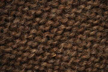 Dark brown wool knitted fabric texture, macro. Close-up view of warm, fuzzy wool yarn in a dense hand-knitted pattern. Natural textile structure with visible fibers and stitches