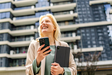 Smile of an albino woman enjoying her day while holding a phone and tablet in front of a modern...