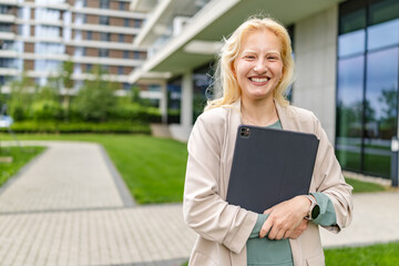 Cheerful albino woman with tablet smiling outdoors in modern urban setting during daytime