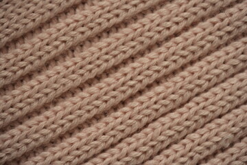 soft pink texture of knitted wool fabric as a background, smooth symmetrical lines of hand-knitted needlework pattern	
