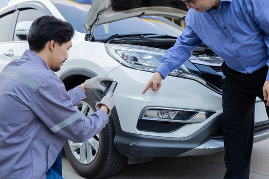 Mechanic taking photo of car damage while customer points at scratch, automotive inspection process for insurance claim or repair documentation, professional service detail in workshop scene - Powered by Adobe