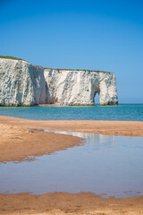 Picturesque Kingsgate Bay in Broadstairs, England, featuring Kingsgate Arch and a sandy beach framed by white chalk cliffs under a clear blue sky