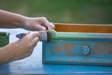 Painting a wooden furniture outdoors, an eco-friendly re-use business.