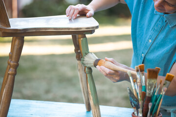 Woman  painting a wooden furniture outdoors, an eco-friendly re-use business.