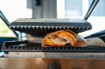 A mouthwatering sandwich that is carefully pressed in a grill, showcasing melty cheese and crispy,...