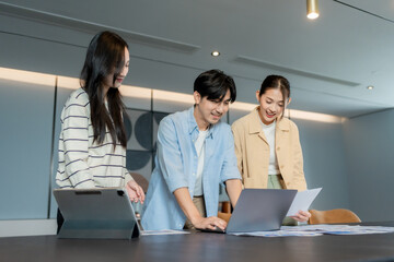 Three asian coworkers discussing ideas and pointing at data charts during a business meeting, actively participating in a collaborative decision process to ensure a successful collaborative decision	
