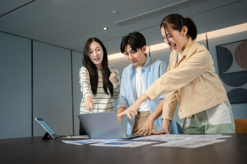 Group of asian business professionals engaged in strategic planning, analyzing charts and discussing ideas around a table during a productive strategic planning meeting in a modern office