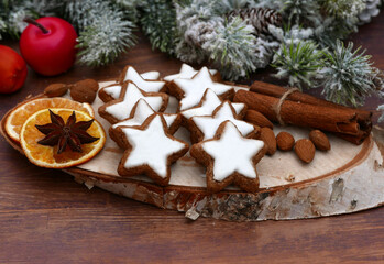 Cinnamon stars with icing between cinnamon sticks and orange slices.