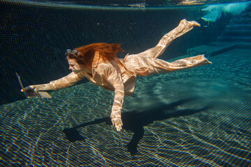 Businesswoman working underwater with laptop in swimming pool