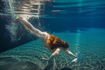 Businesswoman diving in pool with laptop: underwater work and lifestyle concept