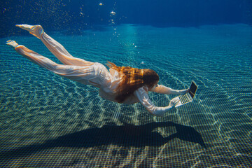 Businesswoman working with laptop underwater in swimming pool