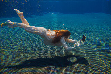 Businesswoman working with laptop underwater in swimming pool