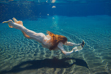 Businesswoman working with laptop underwater in swimming pool