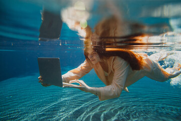 Businesswoman working with laptop underwater in swimming pool