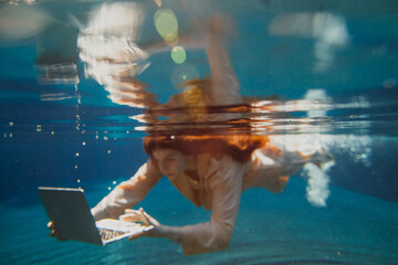 Business professional working underwater with laptop