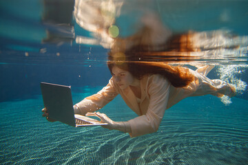 Businesswoman working with laptop underwater in swimming pool