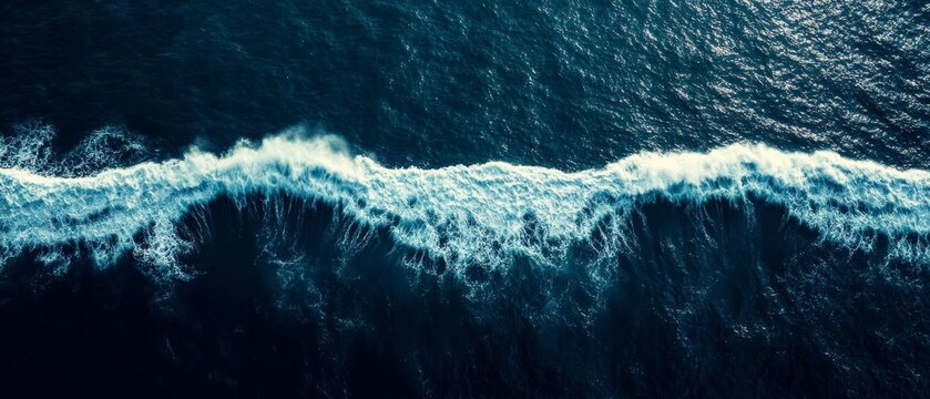 Aerial perspective of powerful ocean waves with white foam cresting against deep blue water, showcasing the raw beauty of nature