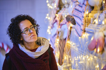 Woman admiring Christmas lights and stockings indoors