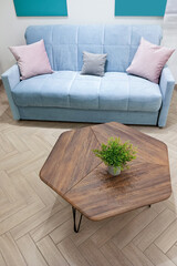 Living room interior, coffee table with wooden tabletop and blue sofa. Parquet floor.