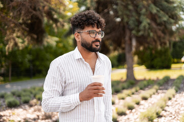 Pensive young man drinking coffee in a park