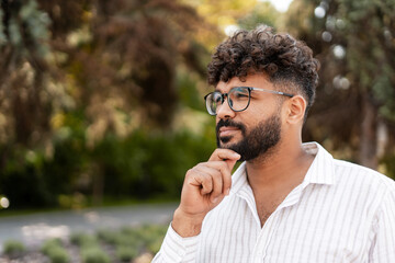 Pensive businessman contemplating in a park, touching his chin