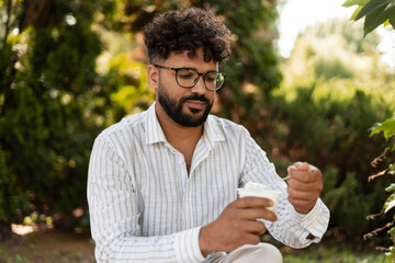Pensive young man enjoying ice cream in a park