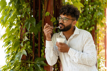 Office worker enjoying a yogurt during his lunch break in a green urban space
