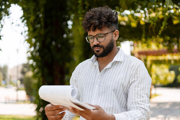 Architect reviewing blueprints in a park, developing sustainable urban project