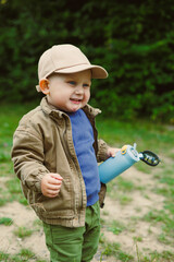 A cheerful child explores nature with a bright water bottle, displaying playfulness, curiosity, and...