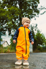 Fototapeta premium An adorable and cheerful toddler dressed in a bright orange rain suit joyfully playing outdoors during a rainy day, showcasing the pure bliss and innocence of childhood in the wet weather