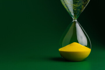 Hourglass and working with limited time, time constraints and countdown. Hourglass photo on green...